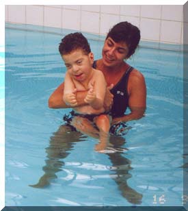Nicholas na piscina com a fisioterapeuta Fl&aacute;via
